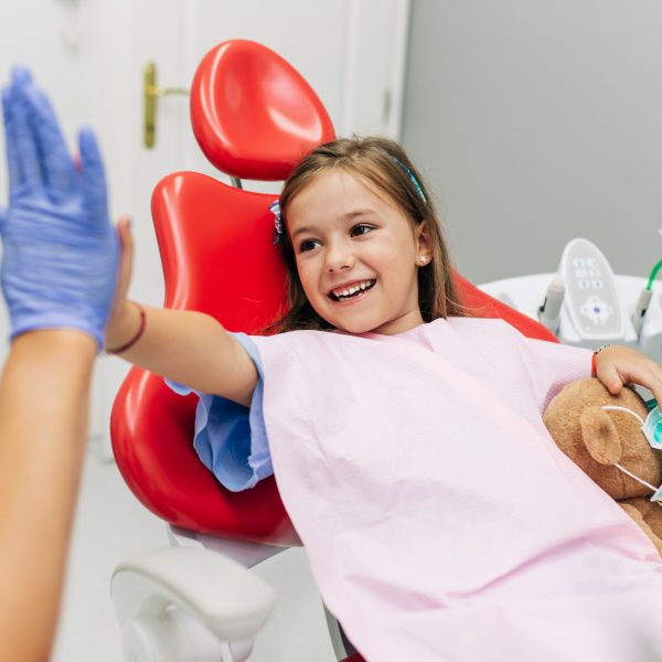 Cute little girl sitting on dental chair and having dental treatment.